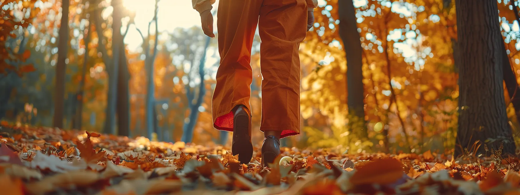 a woman walking through a vibrant forest, her flowing bootcut pants matching the colorful autumn leaves around her.