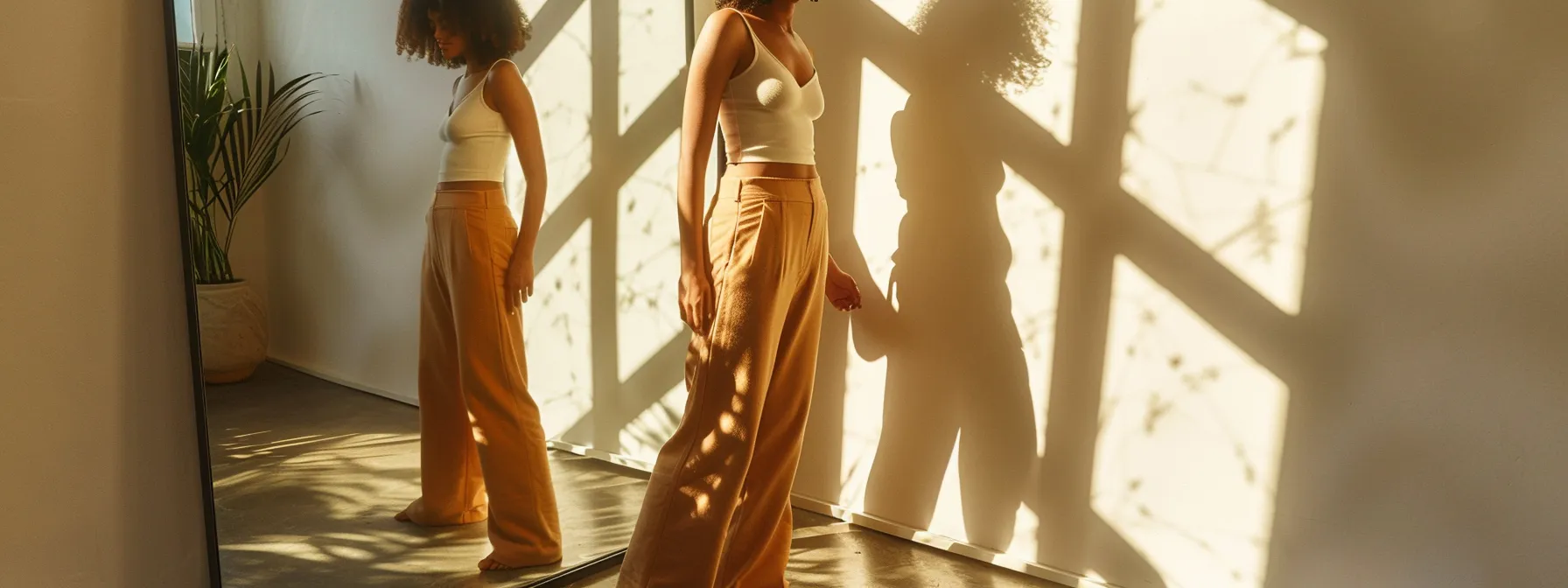 a woman standing in front of a mirror, confidently modeling a pair of figure-flattering, autumn-hued bootcut pants.